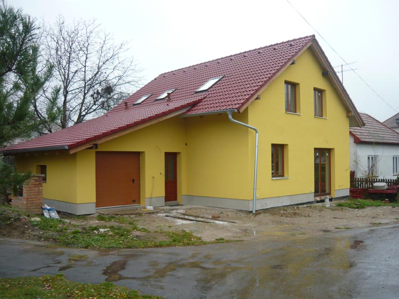 Dokončený rodinný dům se žlutou fasádou a červenou střechou