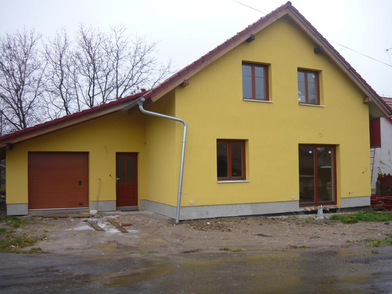 Novostavba rodinného domu se žlutou fasádou a garáží