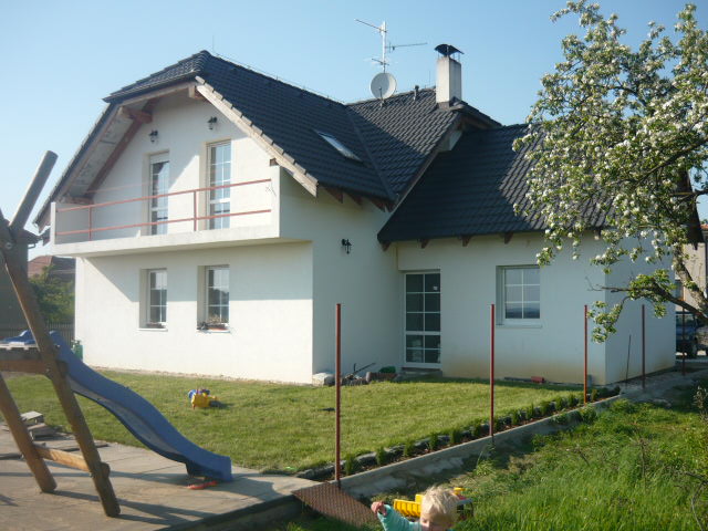 Dokončený bílý rodinný dům s tmavou střechou