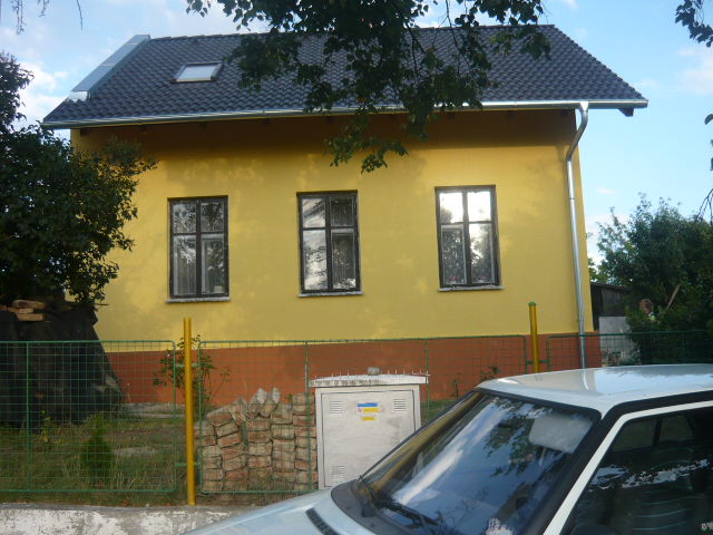 Rodinný dům se žlutou fasádou a tmavou střechou