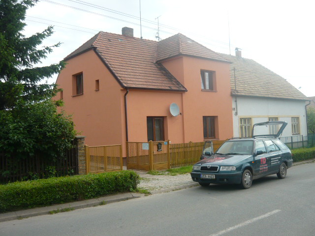 Rodinný dům s oranžovou fasádou u silnice