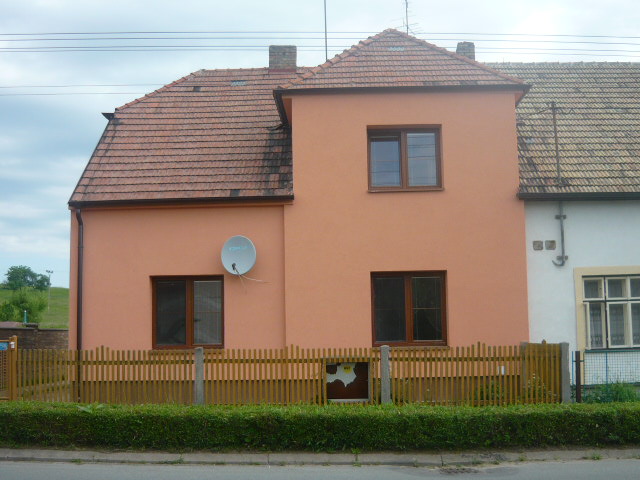 Rodinný dům s oranžovou fasádou a oplocením